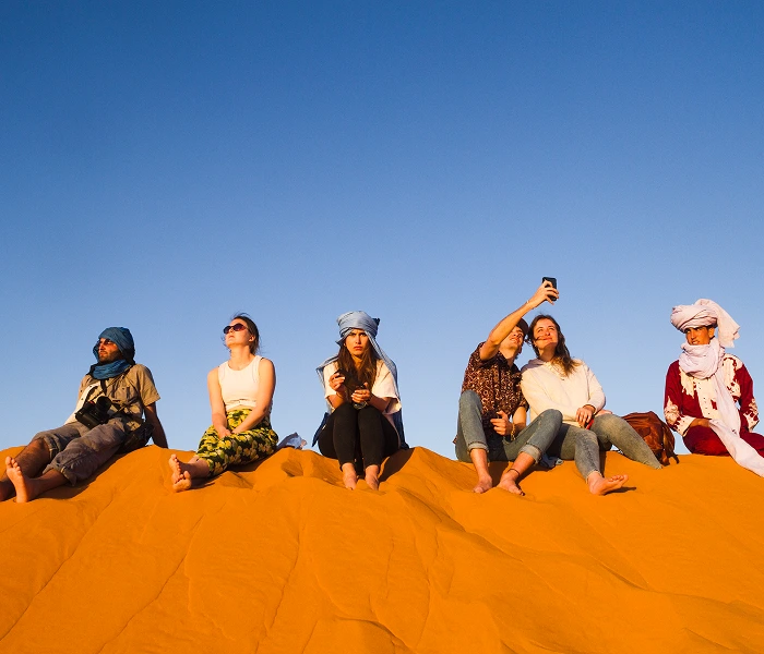 group of people sitting on top of sand dunes